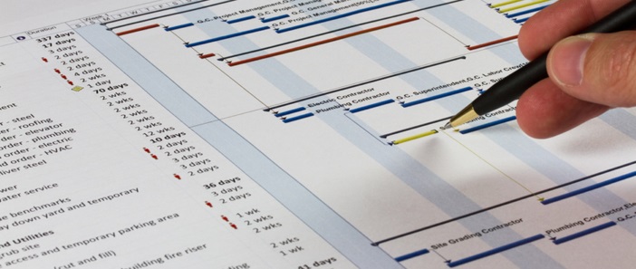 Pen marking a construction schedule (Gantt chart)